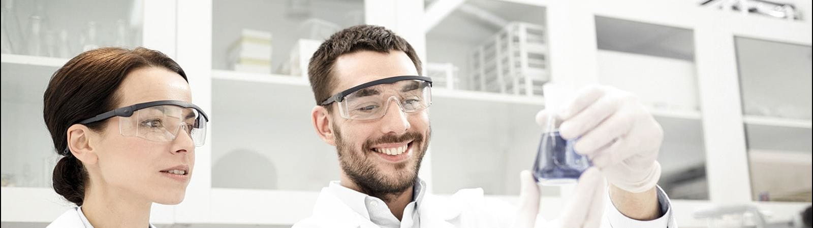 Female and male researchers in a lab holding beaker